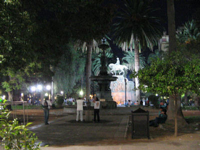 Foto de la fuente de agua, de la Plaza 9 de Julio, resaltada por las luces que la iluminan en la noche.